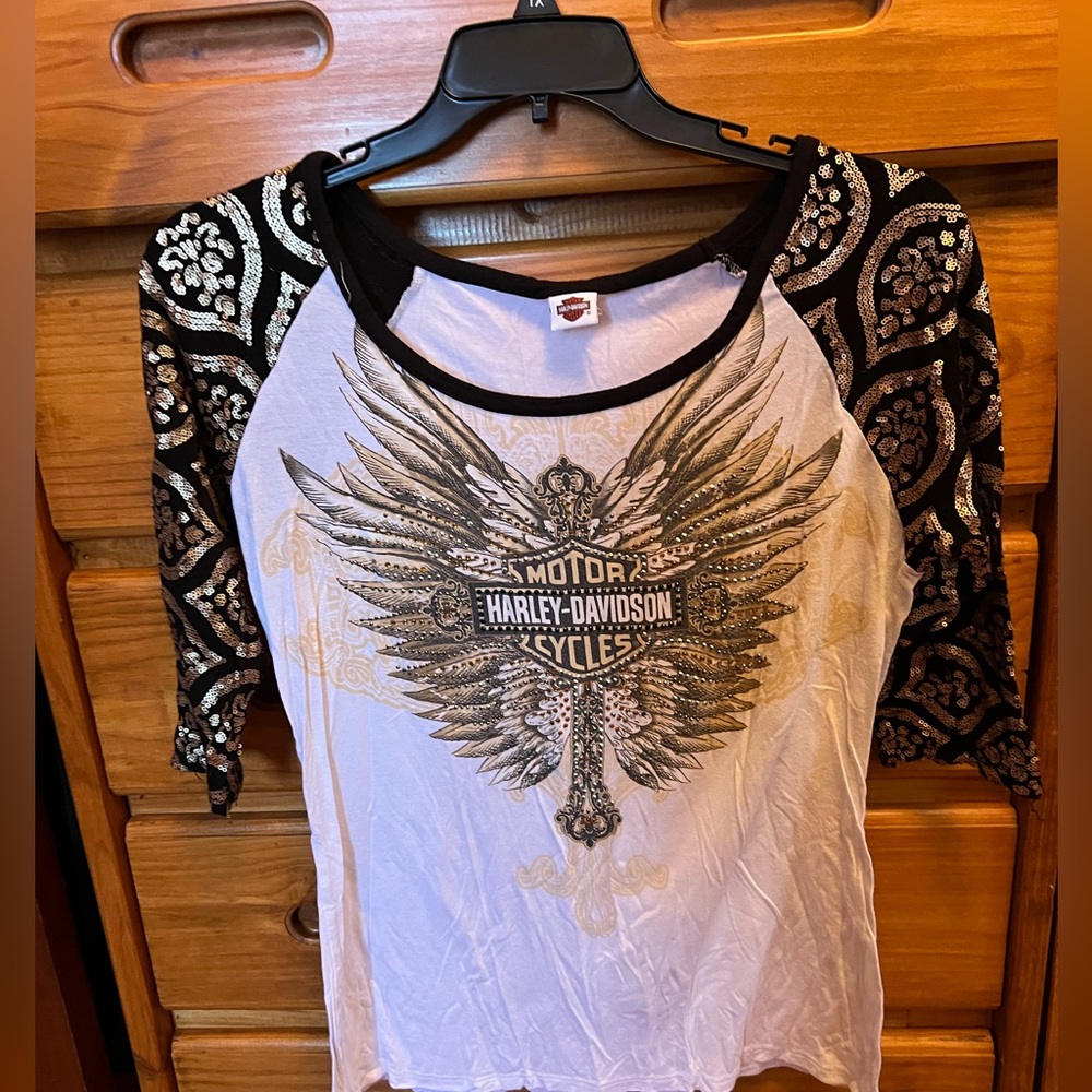 3/4 length sleeve top with sequin sleeves and wings /cross emblem on the front